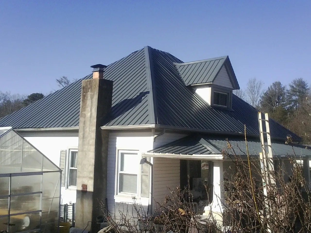 Dark blue standing seam metal roof on a white farmhouse with dormer — Slate & Tile Roof Repair by Roofing Brothers in South Carver
