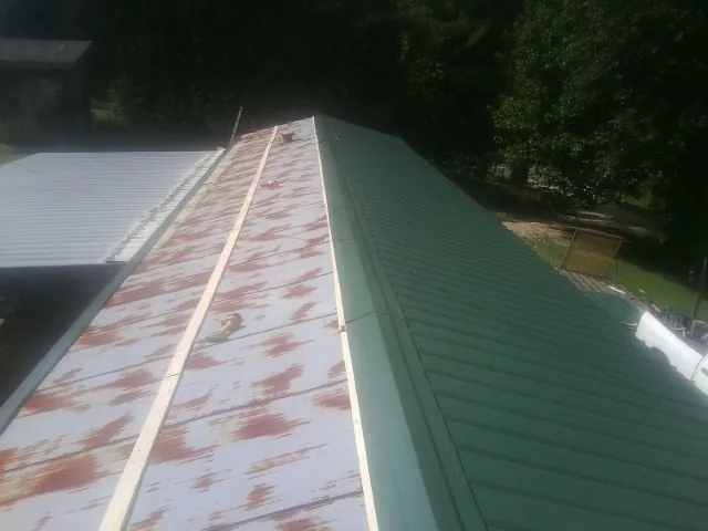 Old rusted panels beside newly installed green metal roofing — Wind Damage Roof Repair by Roofing Brothers in South Carver