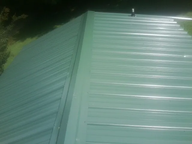 New green metal panels meeting at the ridge of a roof — Flat Roof Repair work by our crew in South Carver