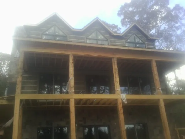Dormers and porch framing on a large log home under construction — Roof Coating work by our crew in South Carver