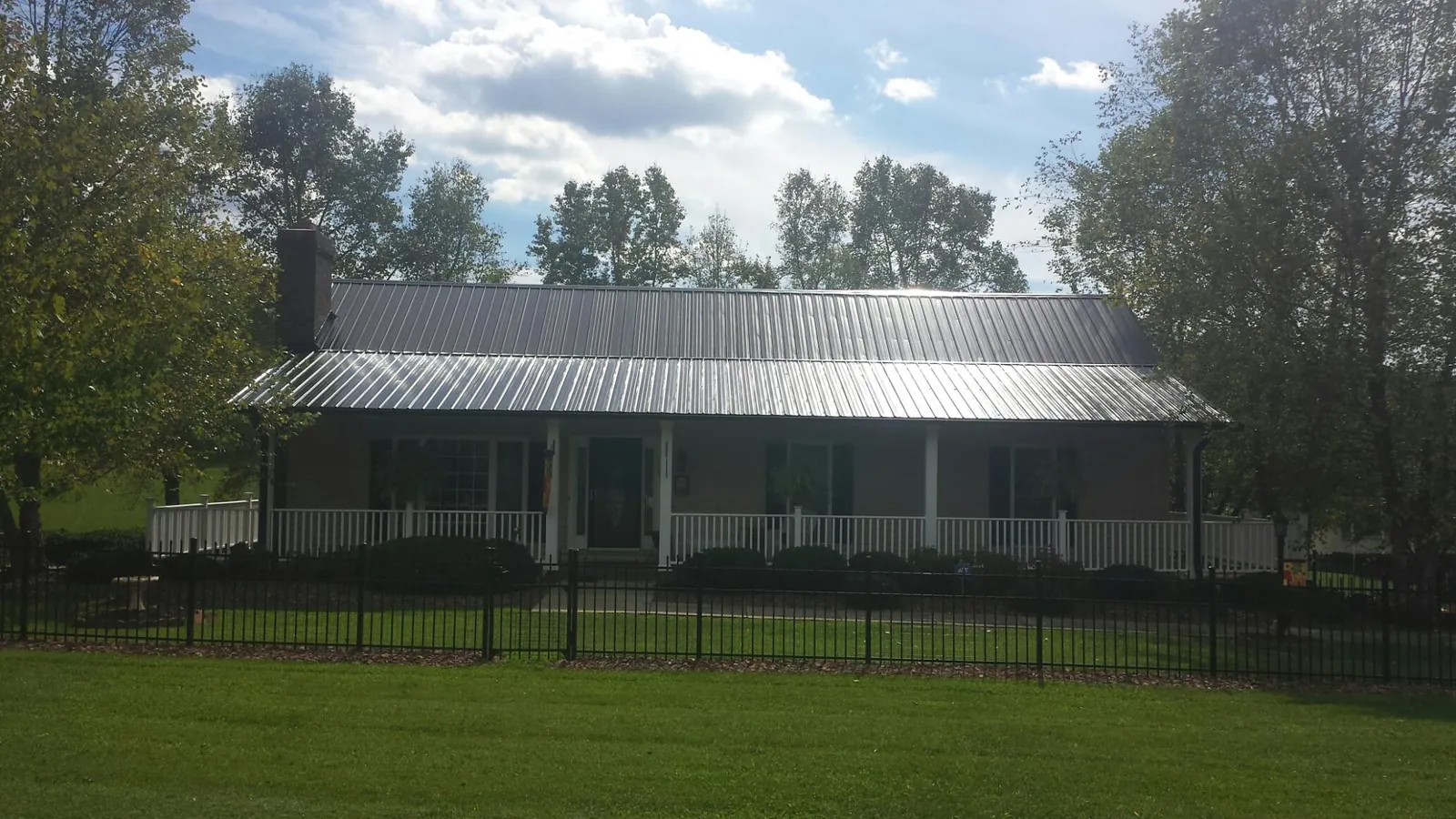 Gray metal roof on a brick ranch with a full width front porch — Gutter Guard Installation work by our crew in South Carver