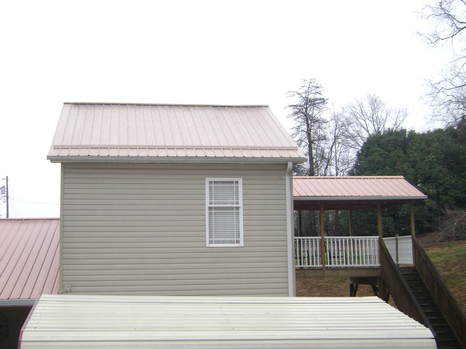 Tan metal roofs on a two story addition and attached porch, from a Roof Replacement job in South Carver