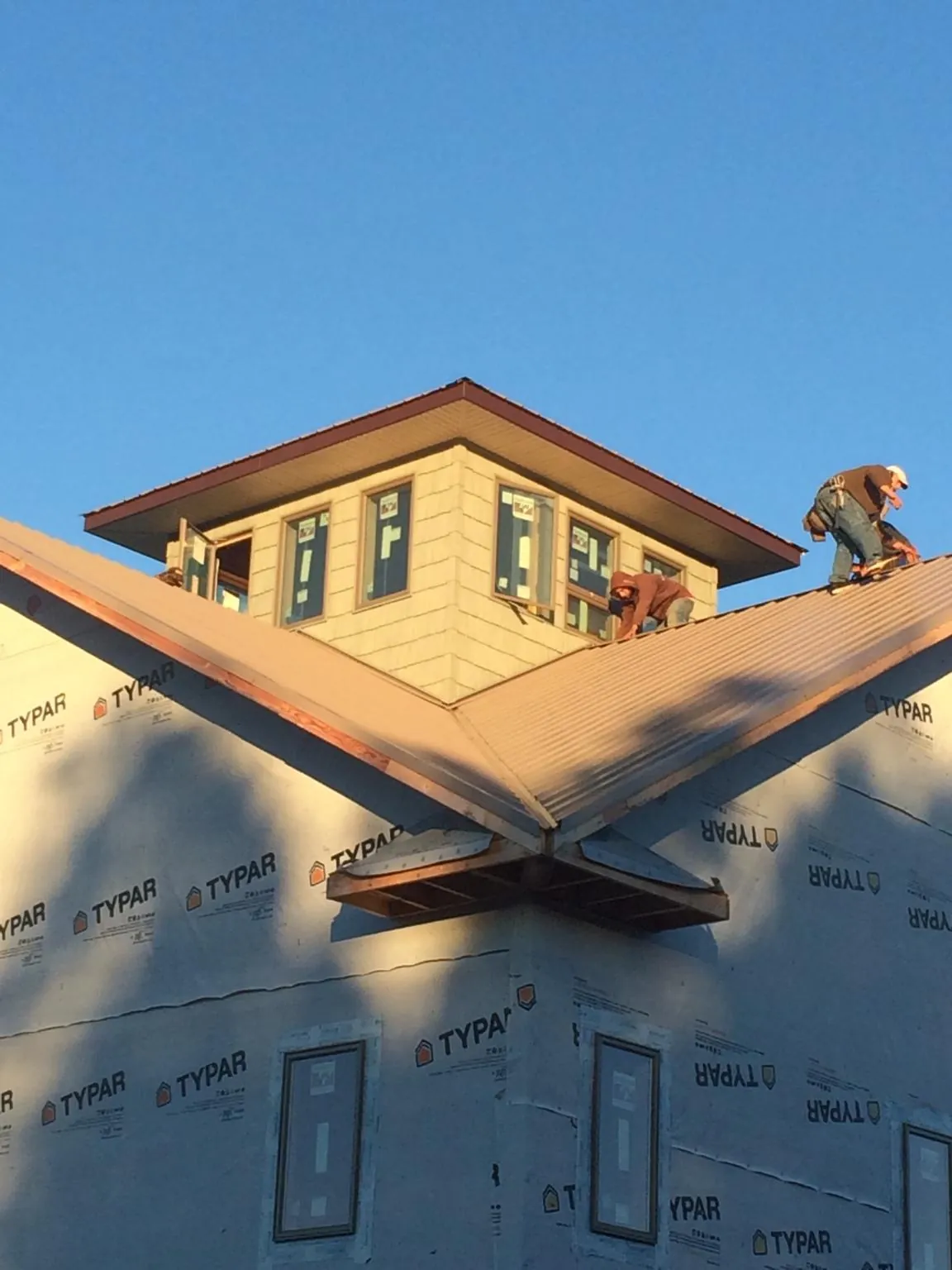 Roofers working around a rooftop cupola on a new metal roof at sunset — Roof Waterproofing in South Carver by Roofing Brothers